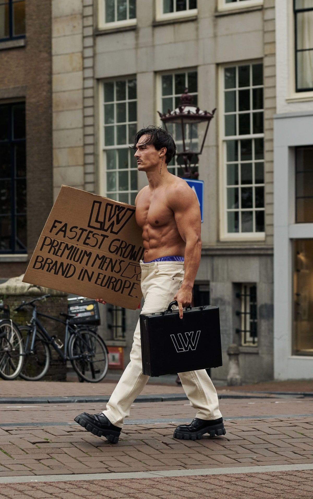 Levy van Wilgen walking through Amsterdam with an LVW sign and case